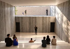 Salle de représentation, violoniste devant un public assis sur les gradins