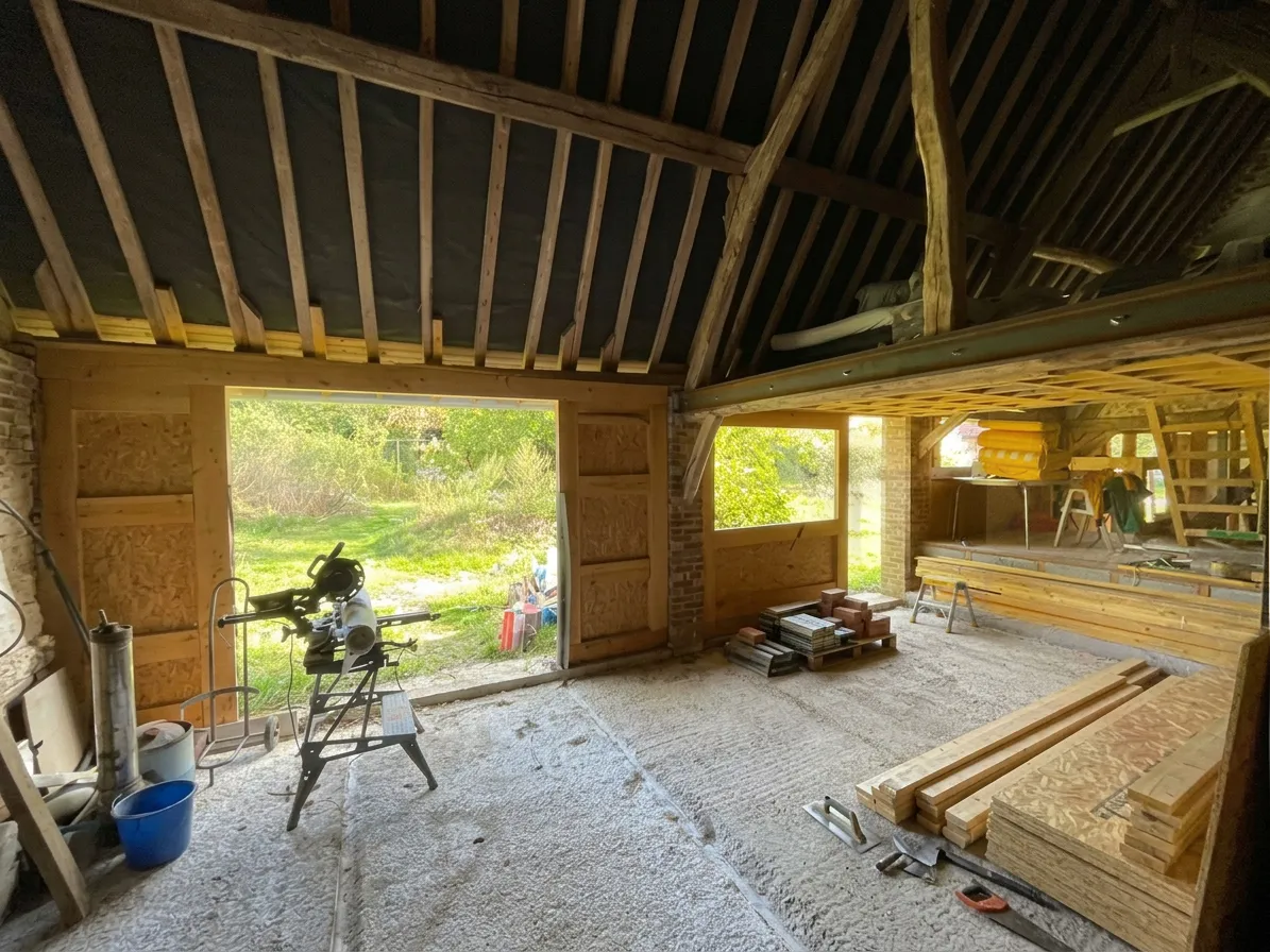 Chantier en cours : charpente ancienne conservée, nouvelles baies et panneaux OSB — Panilleuse, France